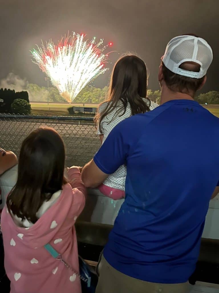 A dad and two girls watching fireworks at a Tioga Downs harness racing racetrack in New York.