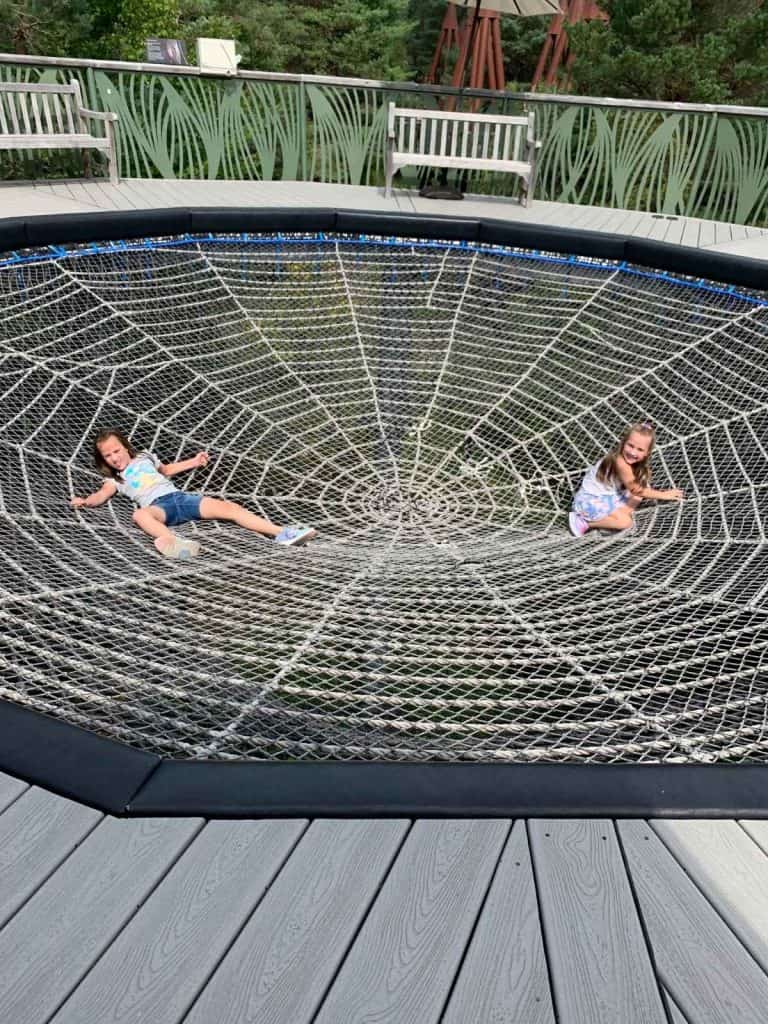 Two children climbing in a large suspended rope spider web at the Wild Center in Tupper Lake, NY.