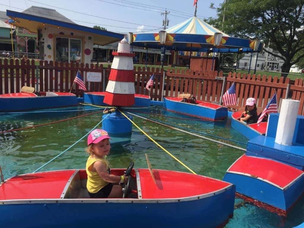 Two children riding in a children's boat ride attraction at the Sylvan Beach Amusement Park in NY.