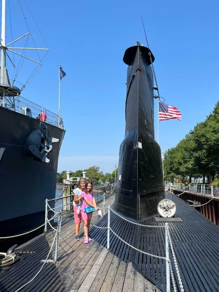 Two family members posing in front of a submarine at the Erie County Naval and Military Park on a sunny day in Upstate NY.
