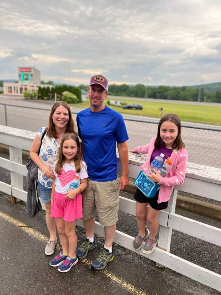 A family of 4 at Tioga Downs Resort in Upstate NY in front of the fence by a harness horse racing track.