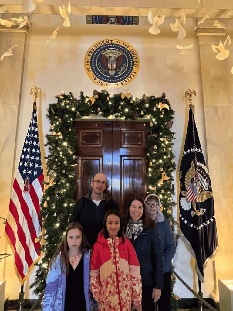 A family photo inside the White House with the Presidential Seal on the wall above them during a holiday tour.