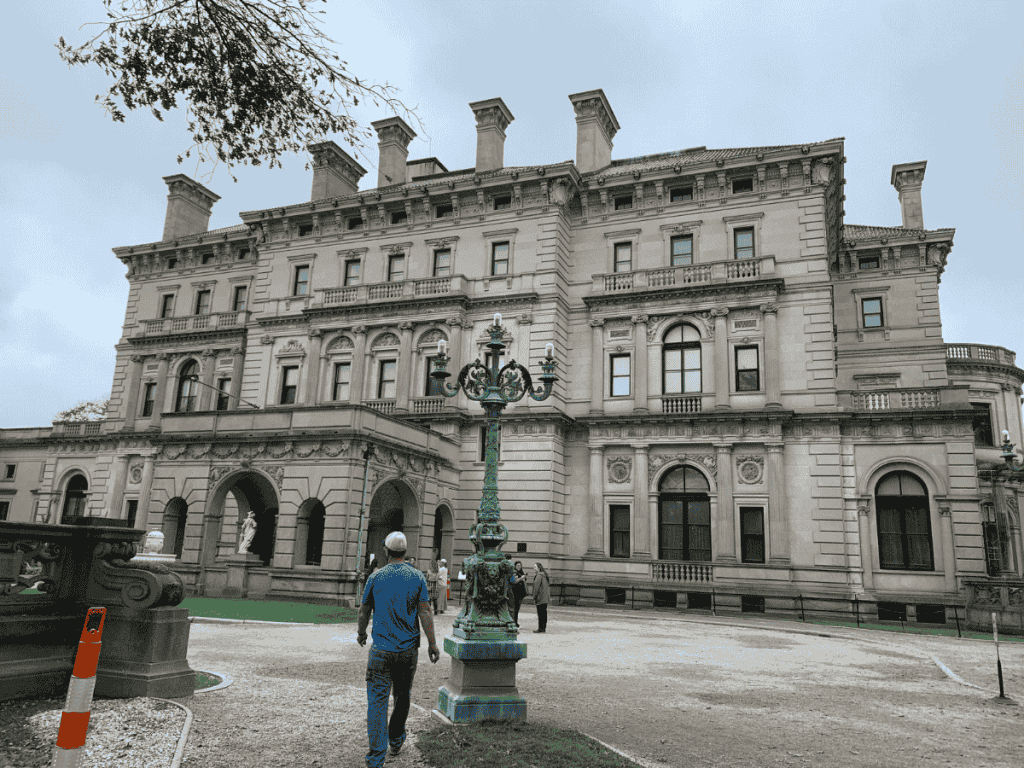 A man walks toward The Breakers mansion in Newport, Rhode Island, showcasing its grand architecture.