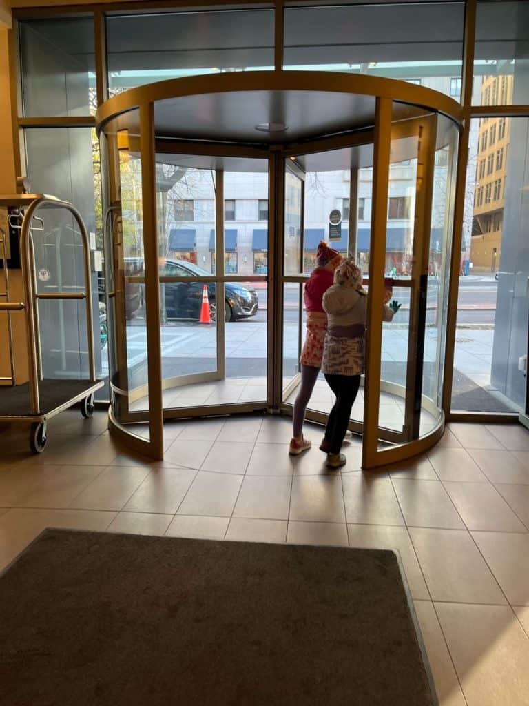 Two kids in winter gear in a hotel revolving door in Washington DC.