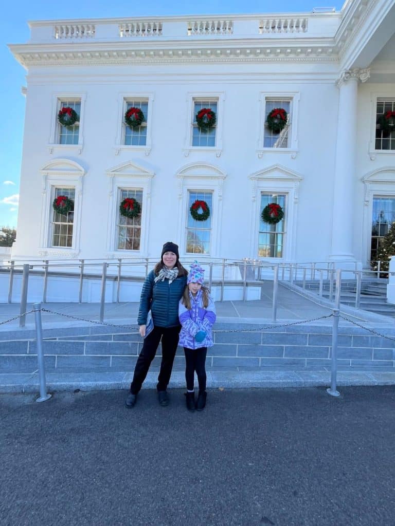 A woman and a girl stands in front of the White House entrance in decorated with wreaths in Washington DC.