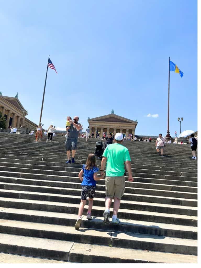 A dad and daughter climbing the Rocky steps at the Philadelphia Museum of Art.