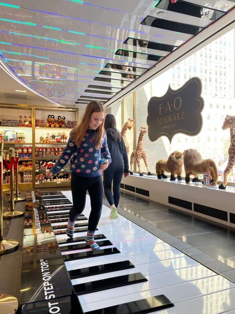 Two girls walk on the floor-sized piano at FAO Schwarz in New York City.
